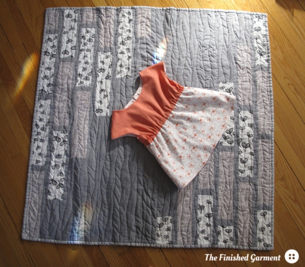 A monochromatic baby quilt and tunic sewn by The Finished Garment.